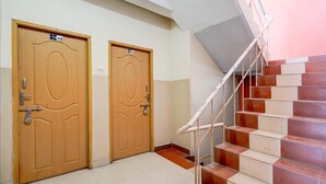 A staircase with a handrail, two wooden doors with numbers, and a tiled floor. - Deluxe BV Stayz (Chennai)