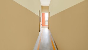 A narrow hallway with beige walls and a tiled floor. - Deluxe BV Stayz (Chennai)