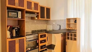 A compact kitchen with wooden cabinets, a stove, and a small bar area.