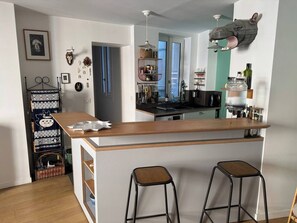 Une cuisine avec un îlot central en bois, deux tabourets et une décoration murale représentant une tête d’animal.