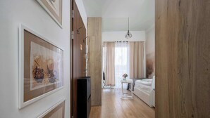Un pasillo que da a un dormitorio con una cama, una mesita y una lámpara colgante.