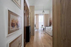 Ein Flur, der in ein Schlafzimmer mit einem Bett, einem kleinen Tisch und einer Pendelleuchte führt.