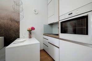 Eine moderne Küche mit weißen Schränken, einem eingebauten Backofen, einer Uhr und einem Blumenvasen auf der Arbeitsfläche.