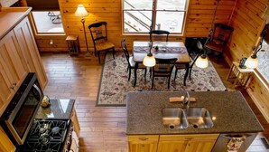 Ein Blockhaus-Interieur mit Küche, Essbereich und Kamin.