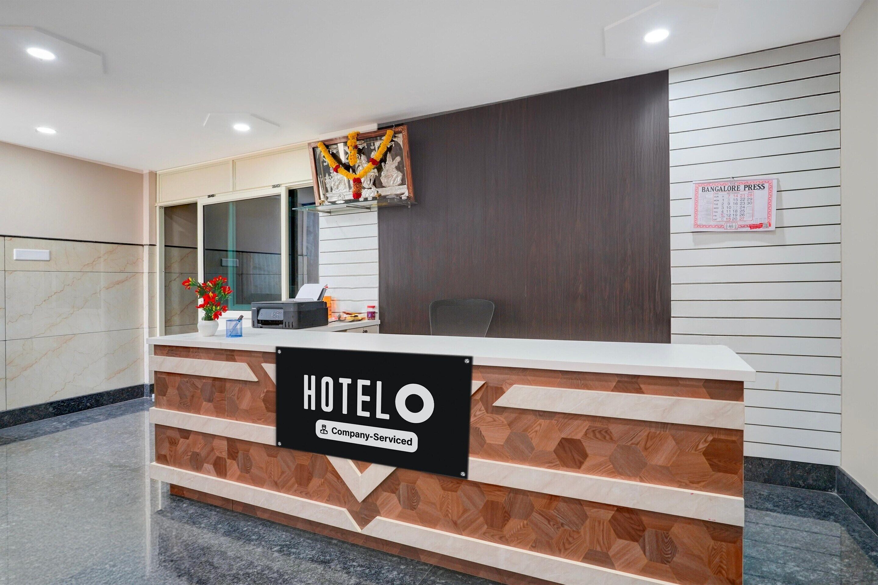 A hotel reception desk with a sign reading 'HOTELO Company Serviced.'