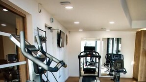 Un gimnasio con cintas de correr, bicicletas estáticas y una máquina de remo.
