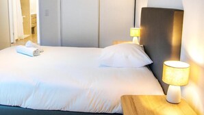 Una habitación de hotel con una cama, una mesita de noche con lámpara y una puerta que da a un baño.