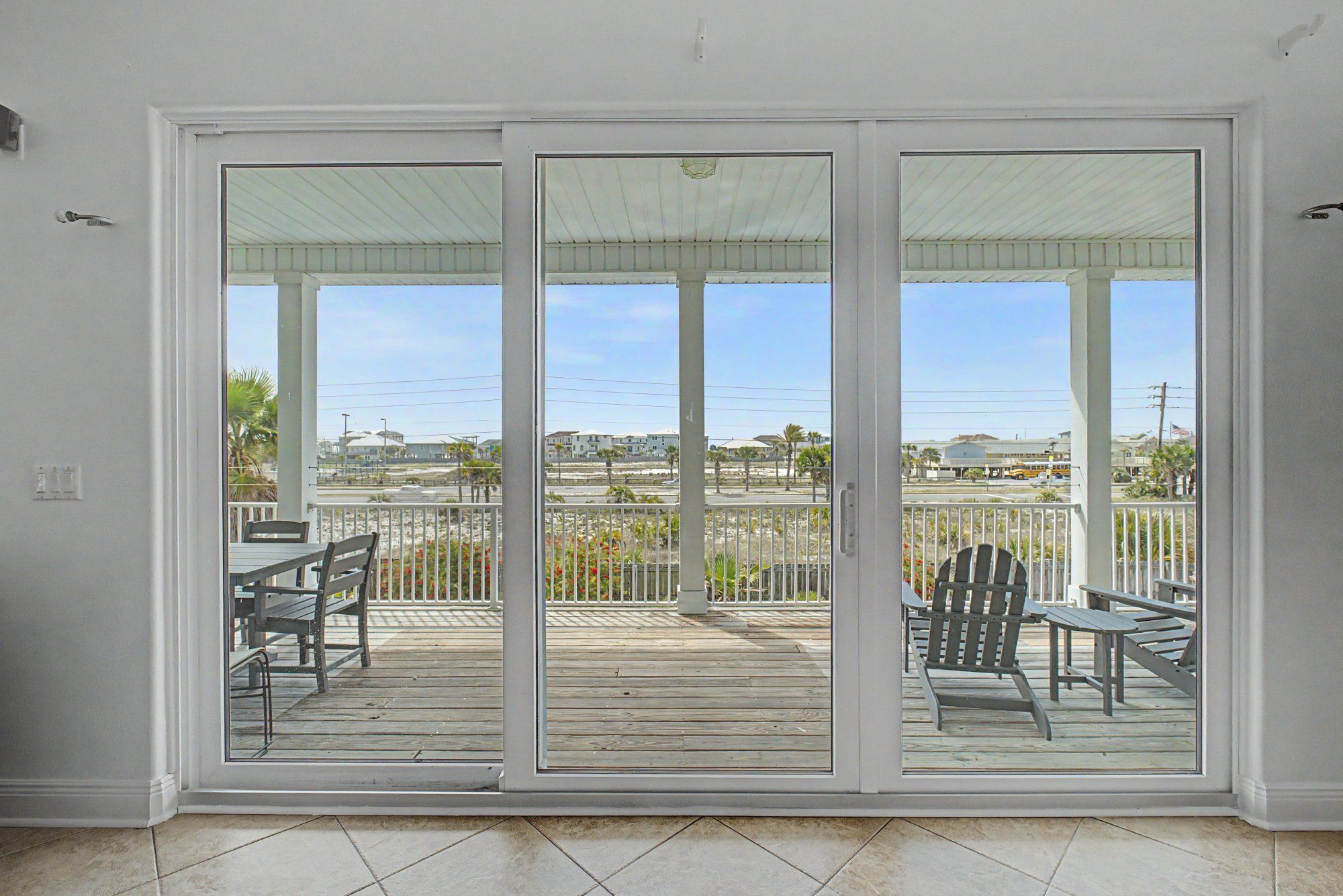 Habitación con puerta de vidrio corrediza que da a una terraza exterior con mobiliario de madera y vistas del entorno.