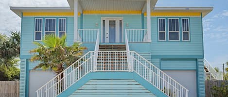 Une maison à deux étages avec un porche à l’avant, un escalier menant à l’entrée et un garage.