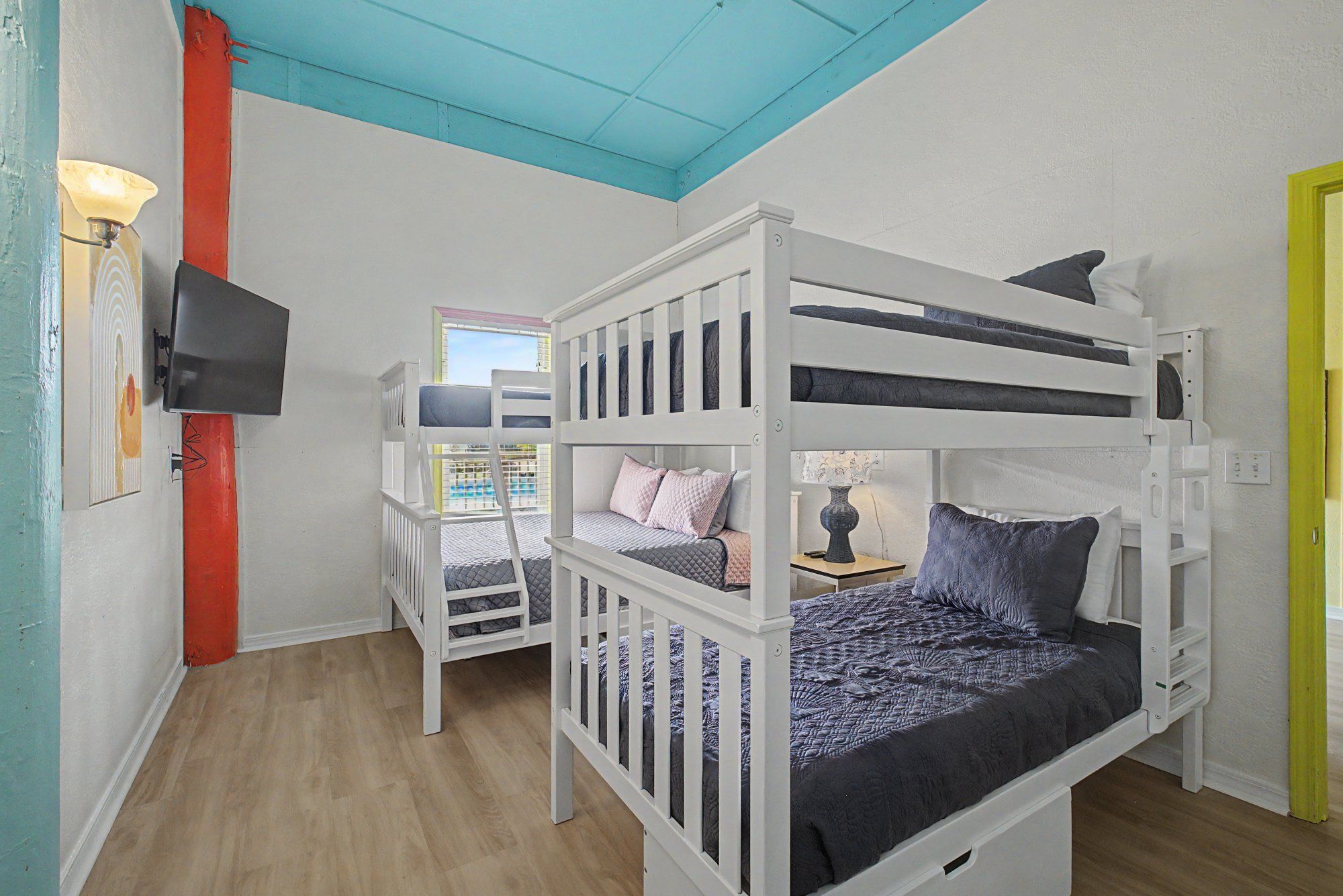 A bunk bed room with a television, a window, and a door.