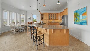 Una cocina amplia con isla central, armarios de madera e iluminación colgante.