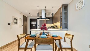 Uma área de refeições com mesa de madeira, cadeiras e um vaso com flores.