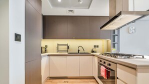 Uma cozinha compacta com fogão a gás, forno e armários modernos.