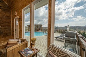 Um deck de madeira com piscina, espreguiçadeiras e churrasqueira.