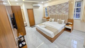 A modern hotel room with a large bed, bedside tables, a TV, and a bathroom door. - Vaikuntha Stays Hotel (Indore)