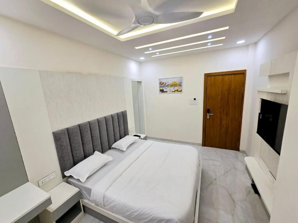 A modern hotel room with a bed, bedside table, TV, and a ceiling fan.
