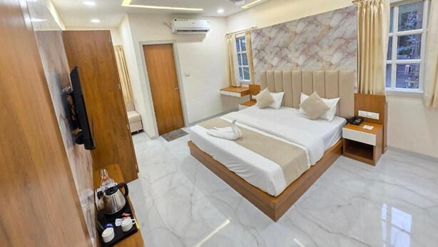 A modern hotel room with a large bed, bedside tables, a TV, and a window with curtains. - Vaikuntha Stays Hotel (Indore)