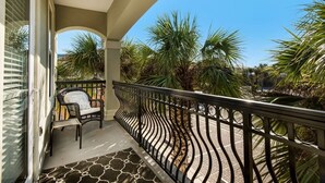 A balcony with a curved black metal railing, a wicker chair, and a patterned rug. - Your Front-Row Seat to Paradise, Pool, Balconies – Sleeps 14 (Miramar Beach)