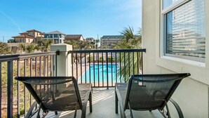 A balcony with two chairs overlooking a swimming pool, surrounded by residential buildings. - Your Front-Row Seat to Paradise, Pool, Balconies – Sleeps 14 (Miramar Beach)