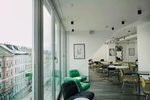 Ambiente moderno con ampie finestre, zona pranzo e vista sugli edifici.