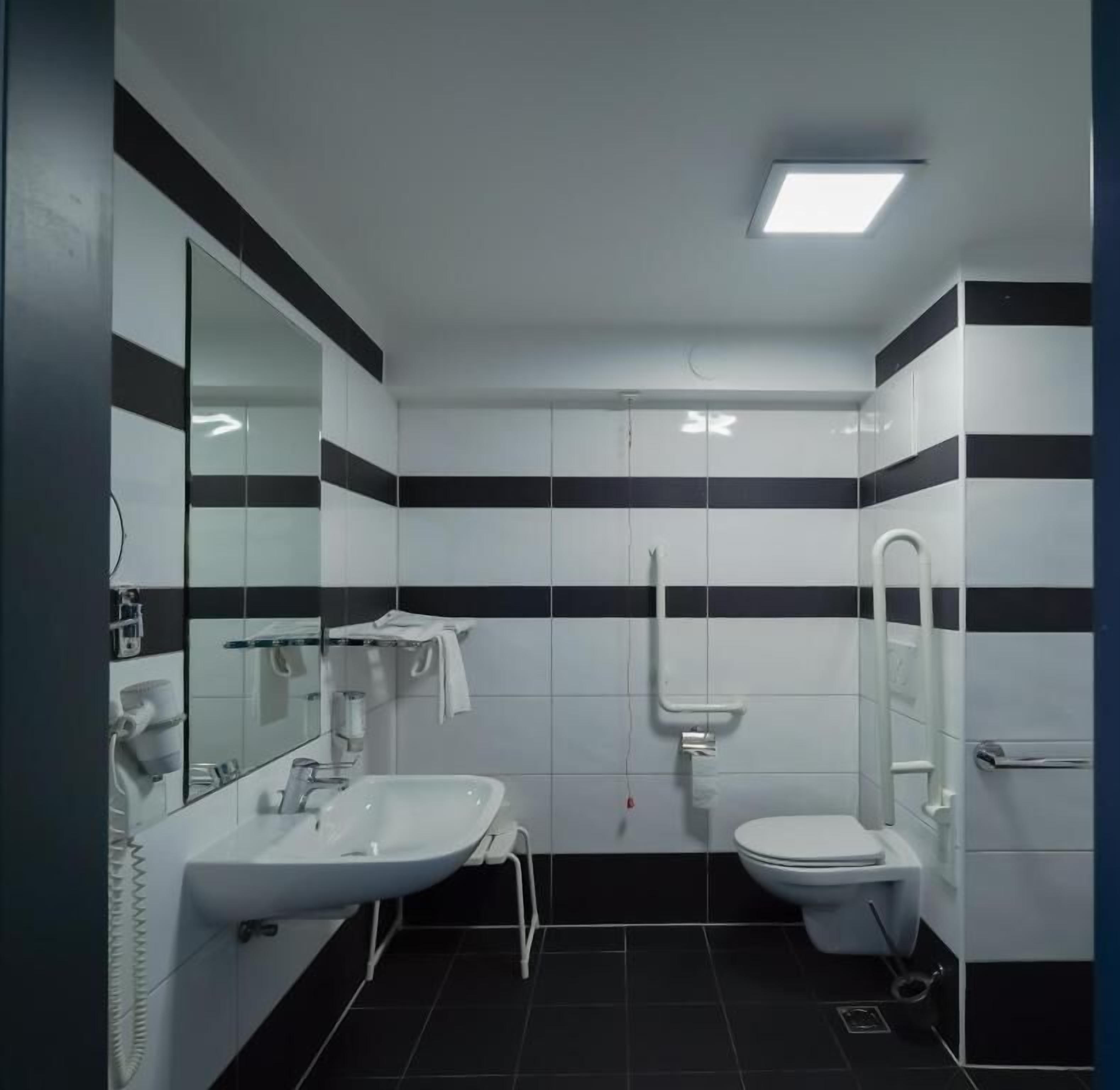 Un baño con lavamanos, inodoro y espejo.