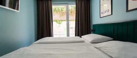 Ein Hotelzimmer mit einem großen Bett, einem Vorhangfenster, einem grünen Kopfteil und einem gerahmten Bild an der Wand.