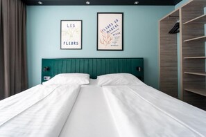A double bed with white linens, teal headboard, and two framed artworks on the wall. - BEE GREEN Schönbrunn Hotel  (Vienna)