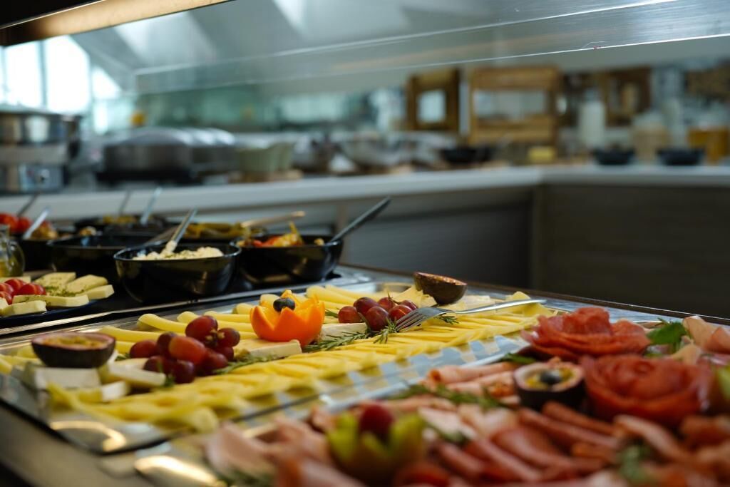A buffet with various food items including cheese, fruits, and meats.