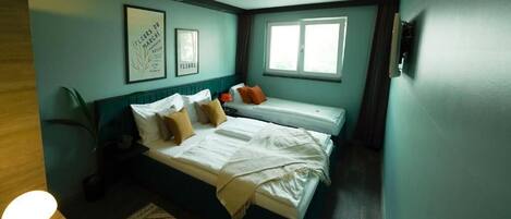 Un dormitorio con cama, mesita de noche, lámpara, cuadros enmarcados y una ventana.