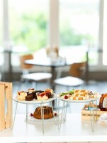 Un'area pranzo con tavoli rotondi, una varietà di dolci e vista sul verde circostante.