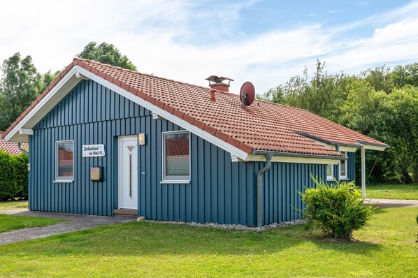 Un petit bâtiment d’un seul étage, avec un toit recouvert de tuiles rouges, une porte blanche et une petite fenêtre.