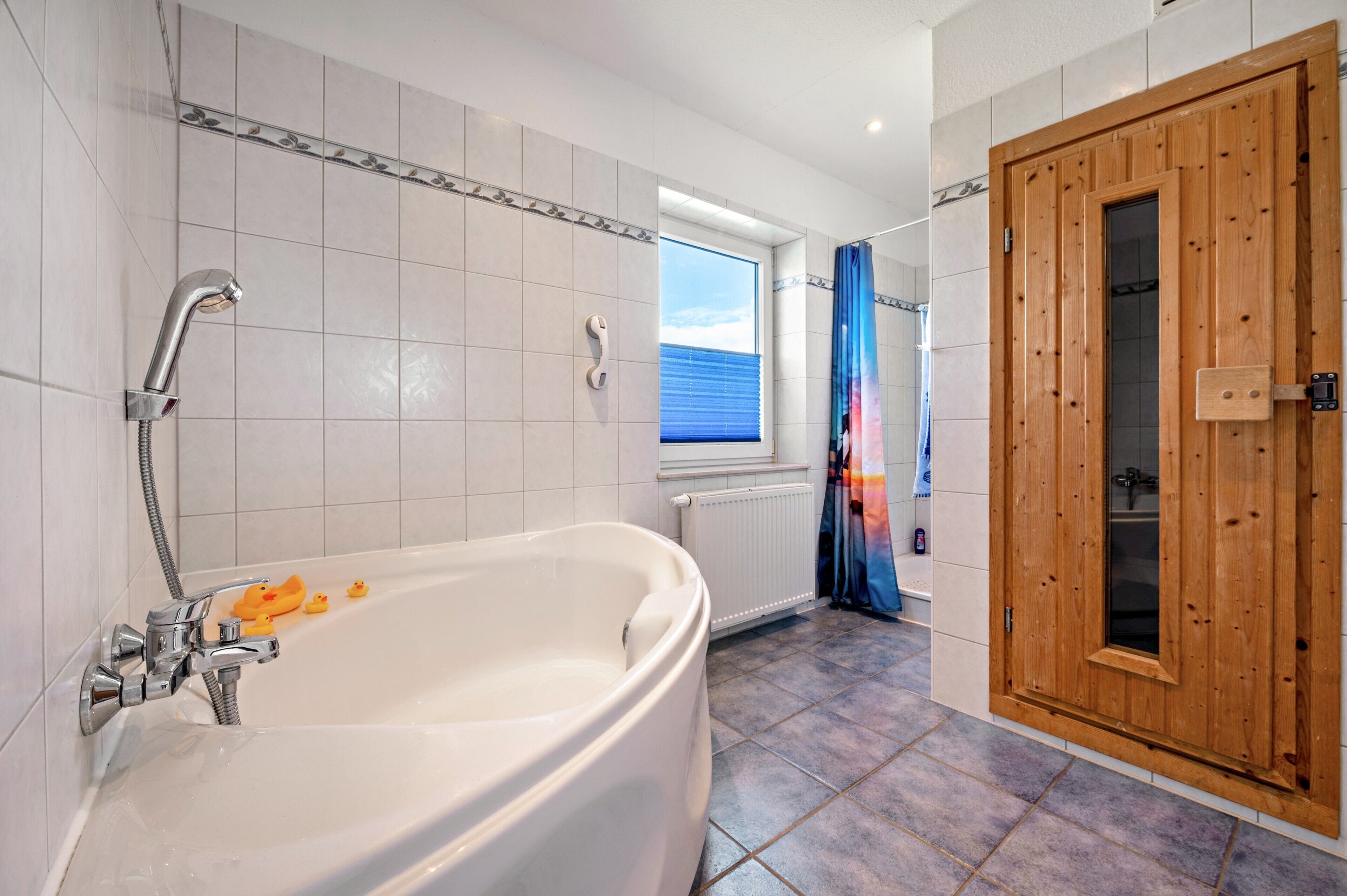 Une salle de bain avec une baignoire sur pieds, une fenêtre offrant une belle vue et une porte en bois.