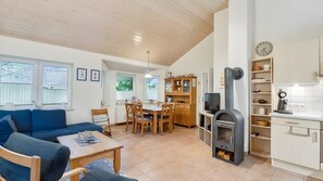 Una sala de estar acogedora con sofá, mesa de comedor, sillas, televisor y chimenea.