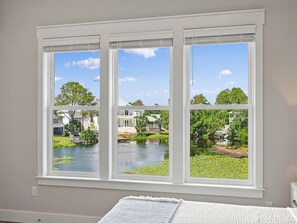 A room with a large window overlooking a lake with houses and greenery. - Salty Seahorse by Southern | Luxe Home, Gulf Views, Private Pool + Fire Pit (Panama City Beach)
