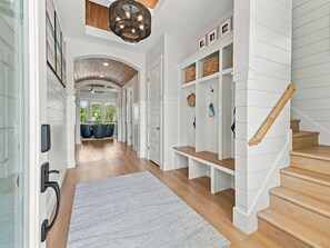 Un couloir avec un escalier en bois, des murs blancs et un ventilateur de plafond.