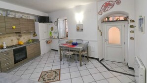 Une cuisine de taille réduite comprenant une table à manger, un réfrigérateur et un sol carrelé.