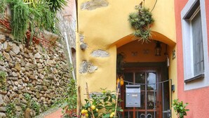 Un bâtiment jaune avec un mur en pierre, une porte en bois et des marches menant à l’entrée.