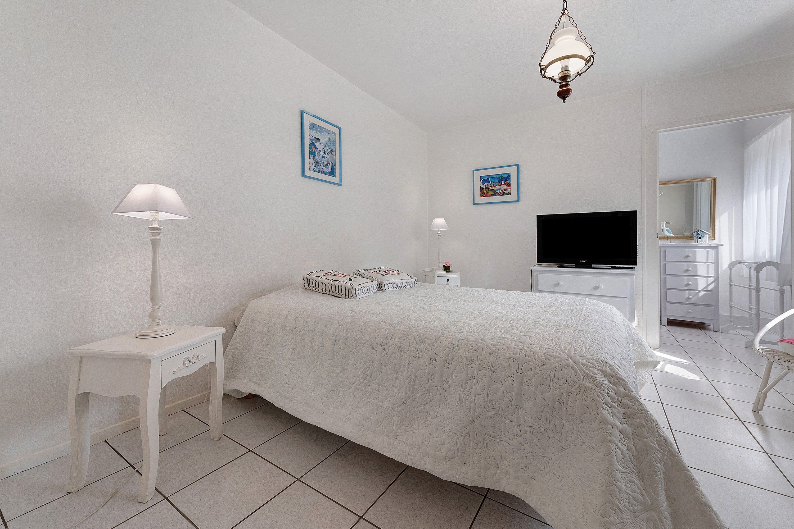 Ein Schlafzimmer mit einem Bett, Nachttischen, einem Fernseher und einer Kommode.