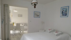 Ein Schlafzimmer mit einem Bett, einem Schreibtisch, einem Stuhl, einer Lampe und zwei gerahmten Bildern an der Wand.