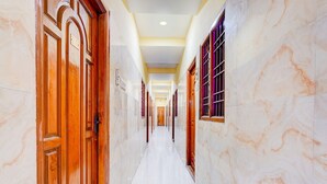 Um corredor com paredes de mármore, portas de madeira e chão de azulejos.