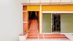 Escadaria levando a entrada de um edifício, com porta amarela e porta de vidro.
