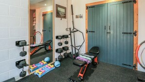 Un gimnàs amb equip d'exercici, un mirall i dues portes.