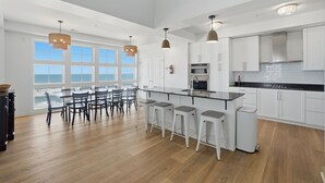 Una cocina moderna con armarios blancos, una isla central con taburetes y luminarias colgantes.