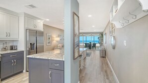 Une cuisine moderne dotée d’un grand îlot central, de meubles de couleur sombre et offrant une vue sur l’extérieur.