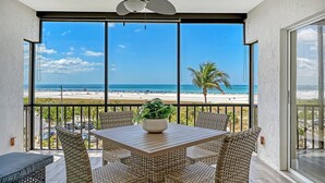 Un balcon agrémenté de meubles en osier, une table avec une plante et une vue sur la plage.