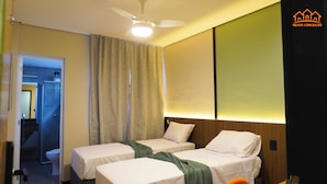 Habitación de hotel con dos camas, ventilador de techo, ducha y baño visible a través de una puerta abierta.