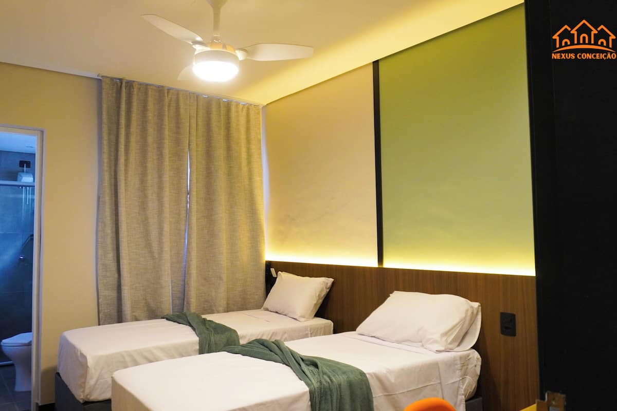 A hotel room with two beds, a ceiling fan, a shower, and a bathroom visible through an open door.