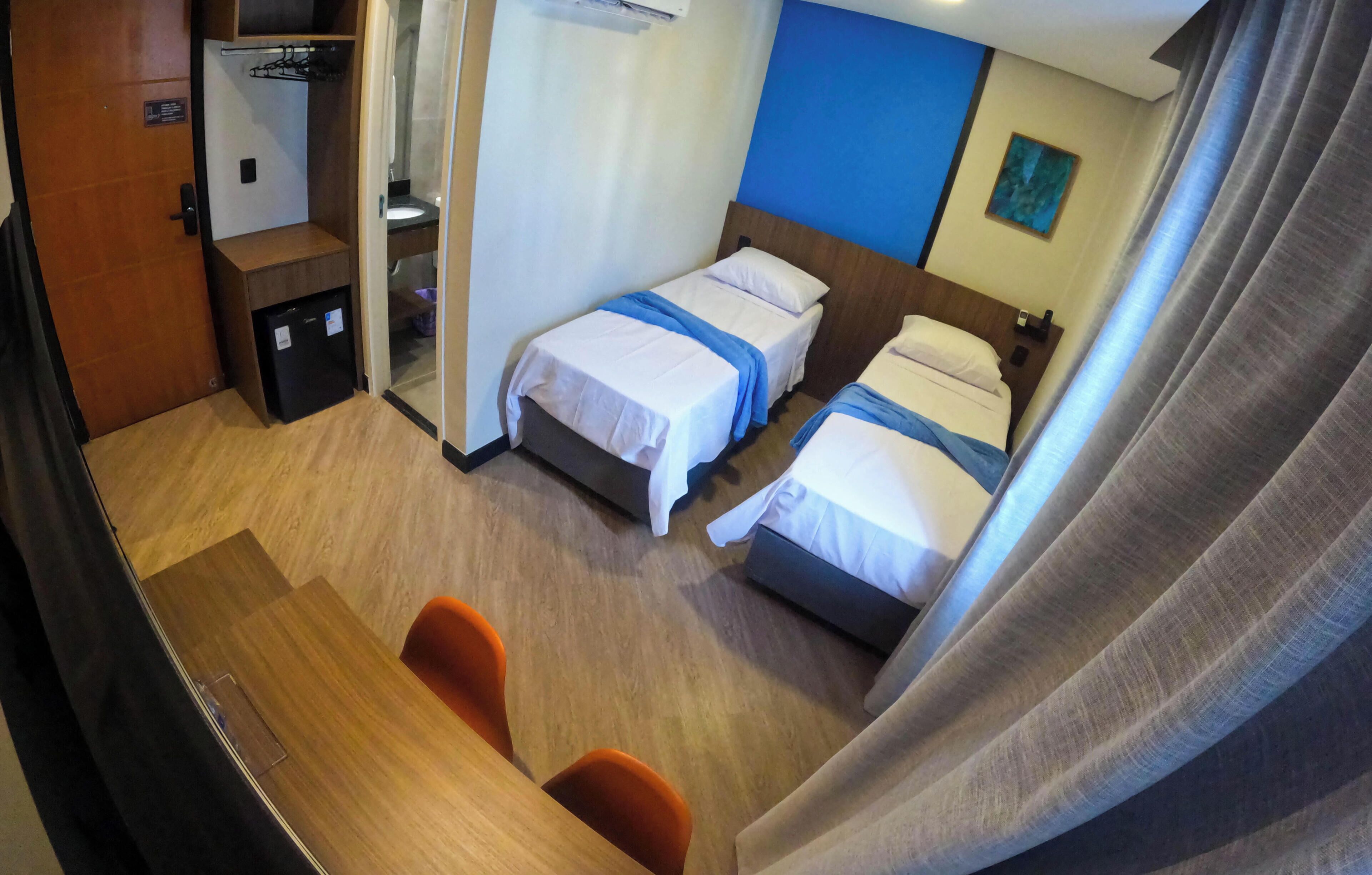 A hotel room with two beds, a desk, and a small seating area.