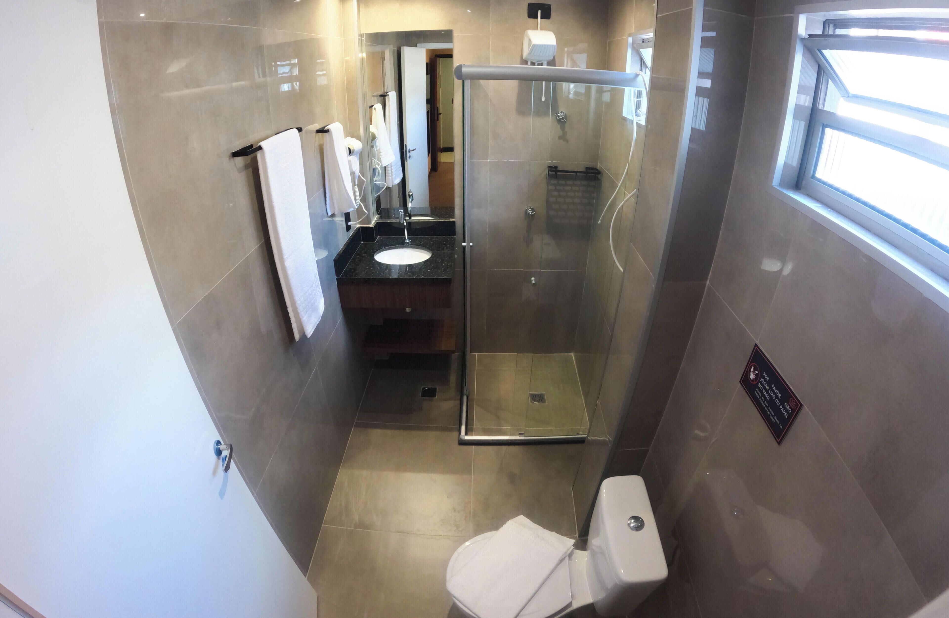 A bathroom with a glass-enclosed shower, a sink, and a toilet.