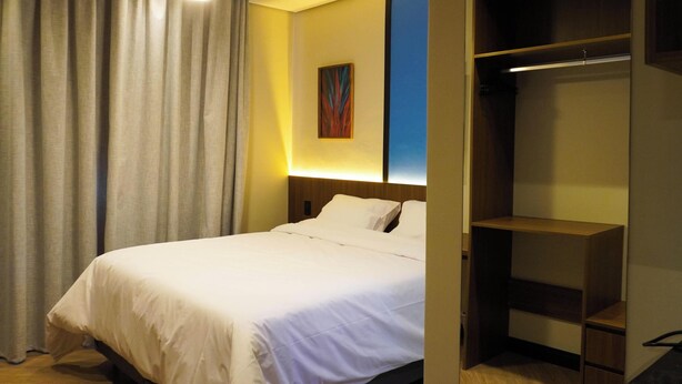 Una habitación de hotel con una cama, un armario y un cuadro en la pared.